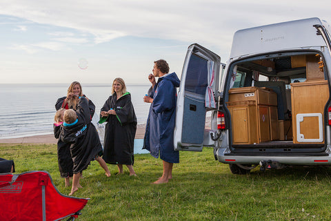 Family keeping warm by the sea wearing their dryrobe changing robes. 