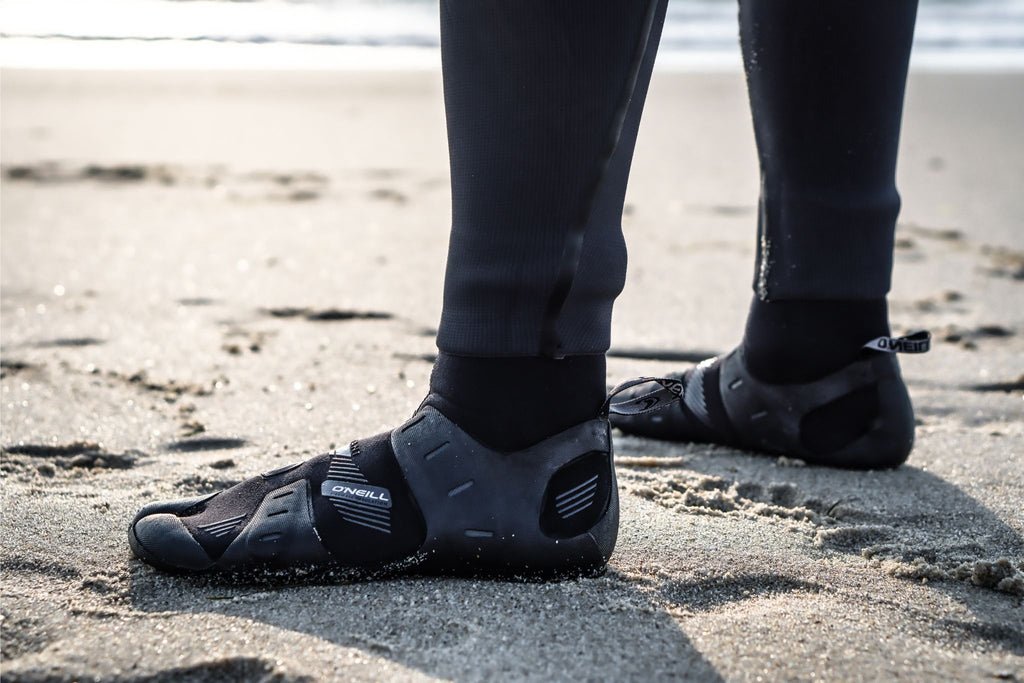 Person on the beach wearing O'Neill mutant split-toe neoprene boots