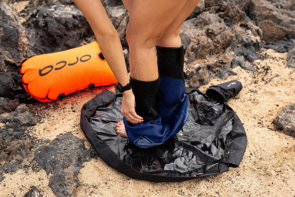 Person getting changed on top of a changing mat on the beach.