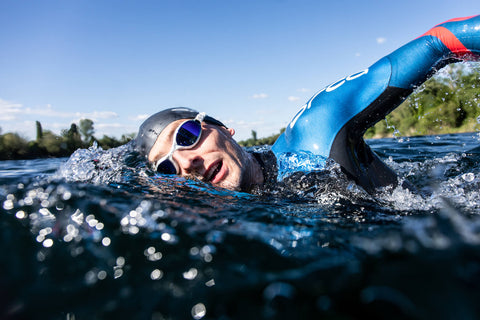 A man swimming in open water while wearing an Orca triathlon wetsuit. 