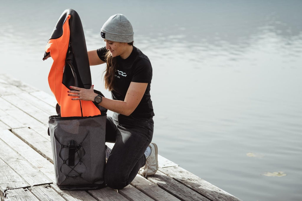 Woman taking an open water swimming wetsuit out of her dry bag