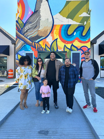 Anthony and his friends and family standing in front of a vertical mural.