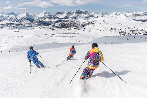 Skiers in powder at Banff with mountains in the horizon