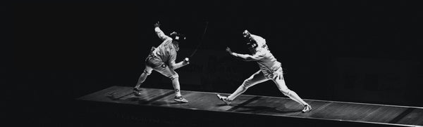 Two fencers leaping at each other in white uniforms and masks