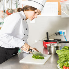 Chef in a kitchen slicing salad