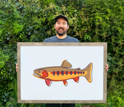Artist Robin McCormack holding a print of a golden trout