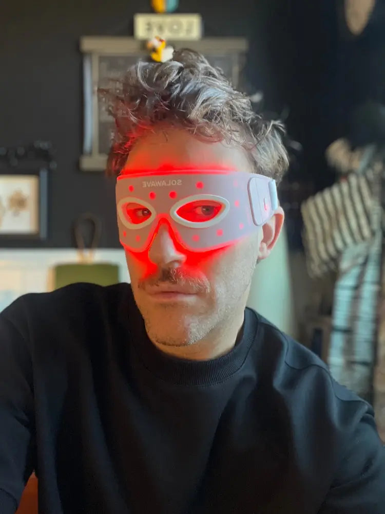 Person wearing a glowing LED facial mask indoors.