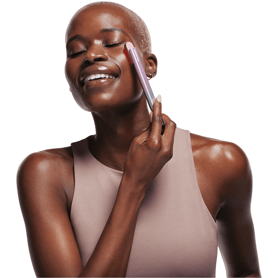 A woman uses a skincare wand on her cheek.