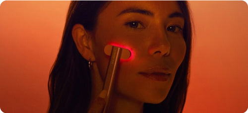 امرأة تستخدم عصا الضوء الأحمر على وجهها