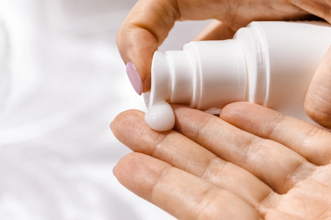 Woman moisturizing her hands with hand lotion to prevent dry skin.