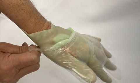 Putting a disposable glove over paraffin wax hand to lock in heat