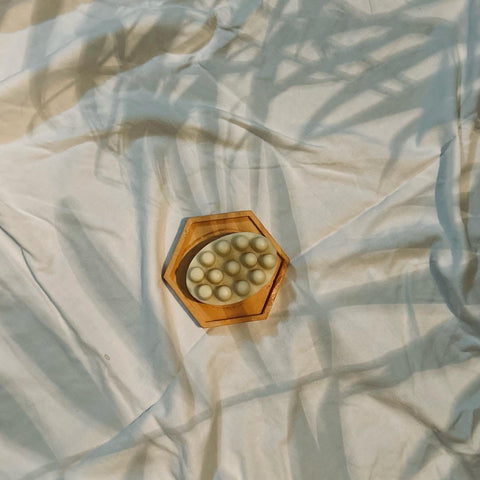 massage bar laying on white bed sheets with shadow