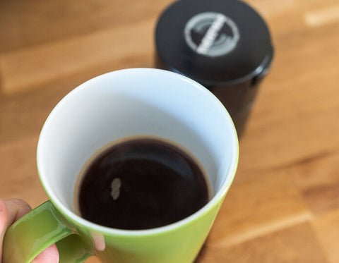 fresh coffee in a mug with storage container in background