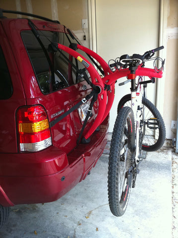 red car with one bike hanging on bike rack 