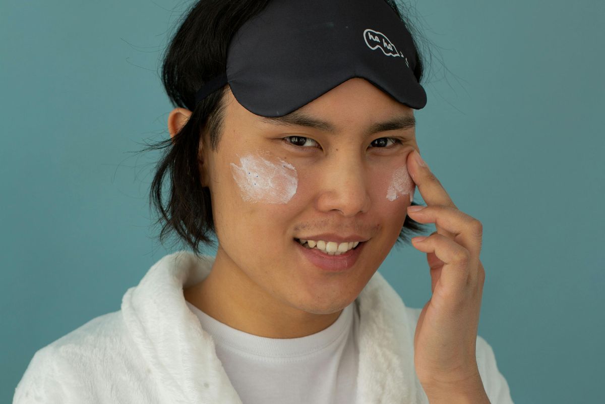 man wearing eye mask and applying skincare to his face