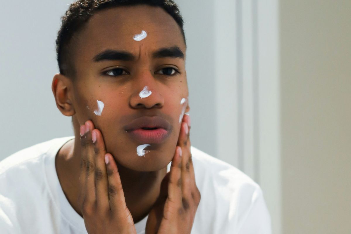 man putting moisturiser on his face