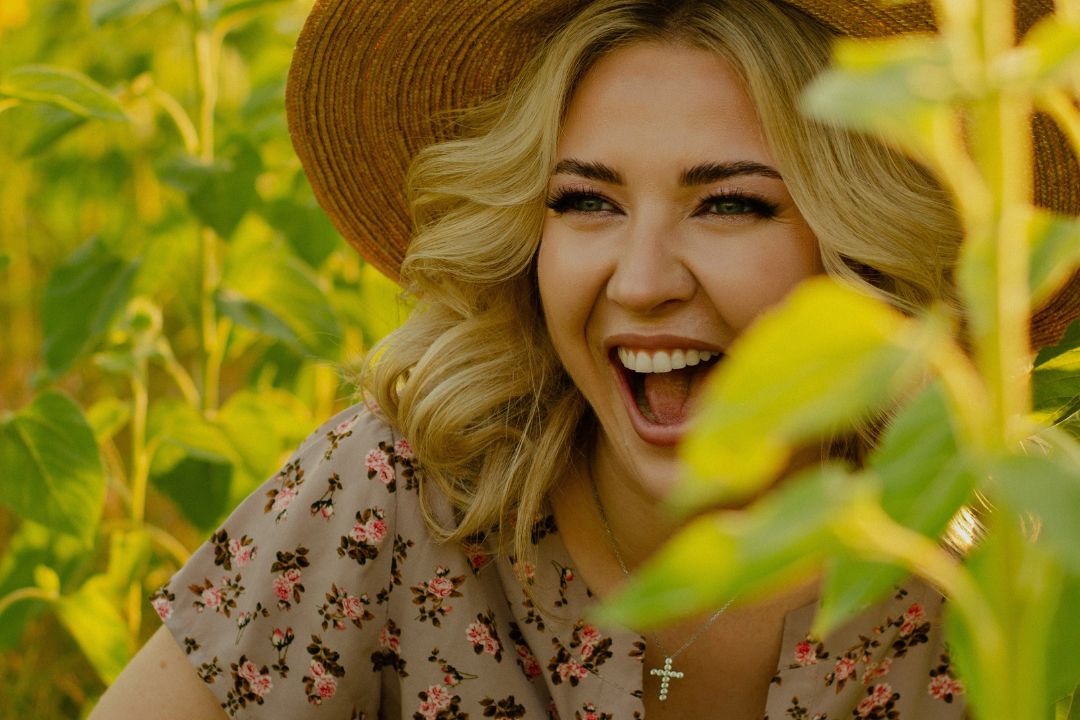 woman smiling in the middle of a sunflower field