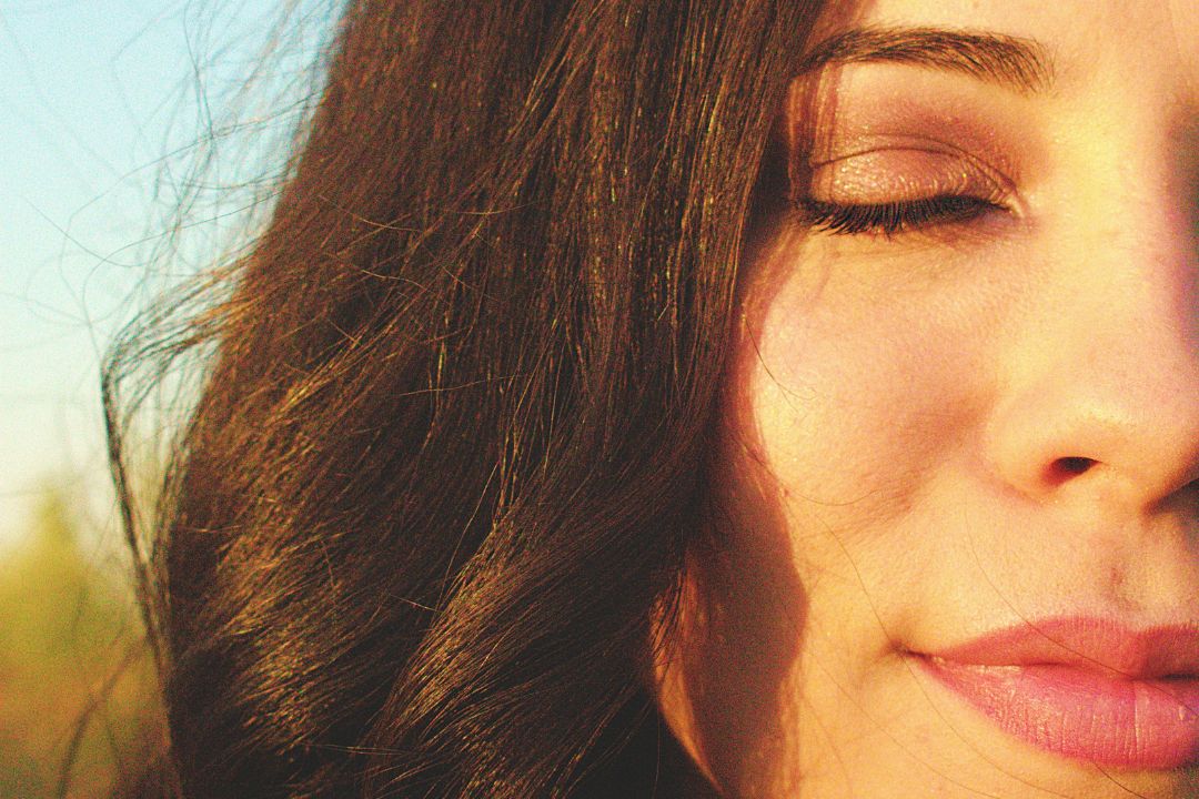 close up of woman with her eyes closed and sunshine on her face