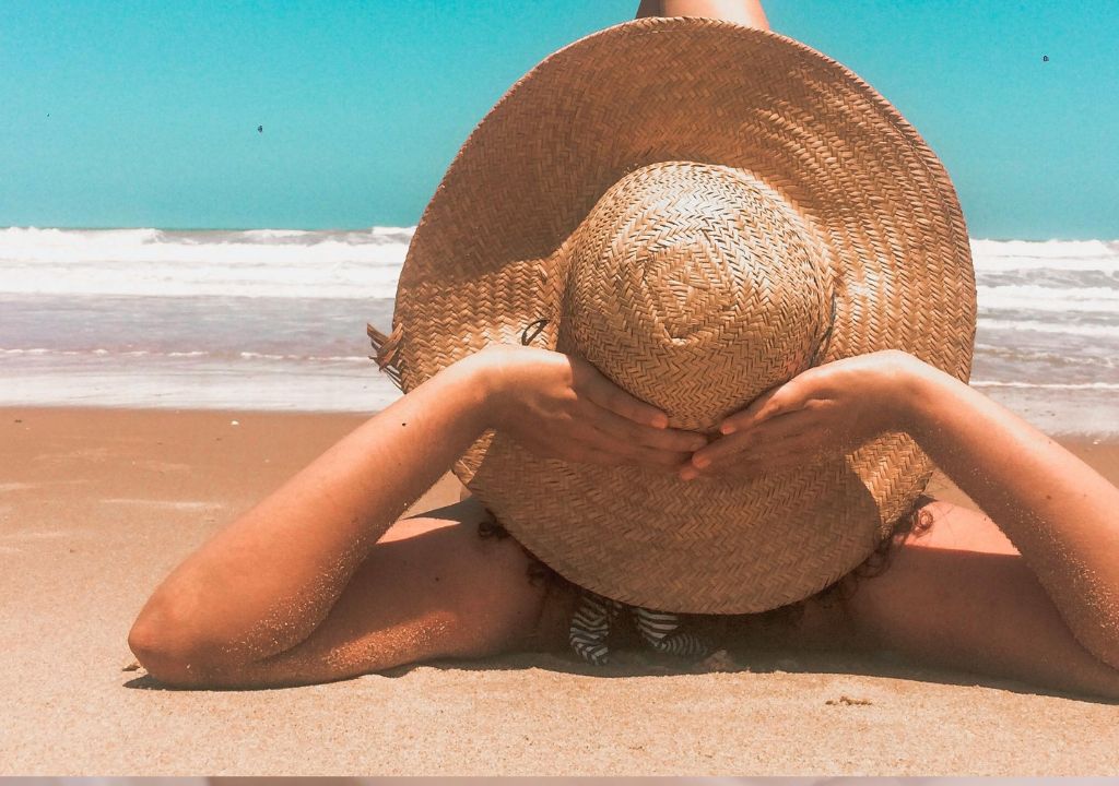 lady in hat sunbathing on the beach