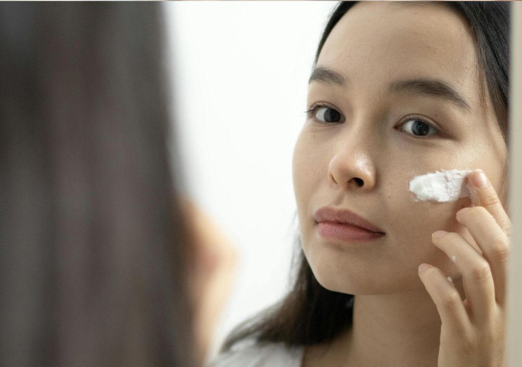 Lady applying sunscreen in the mirror