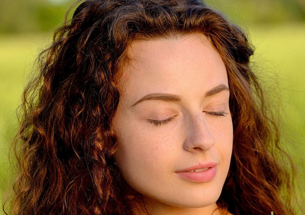 closeup of a lady in a field with the evening sun on her face