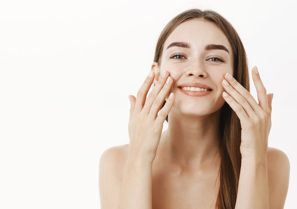 young smiling lady applying moisturiser to her face