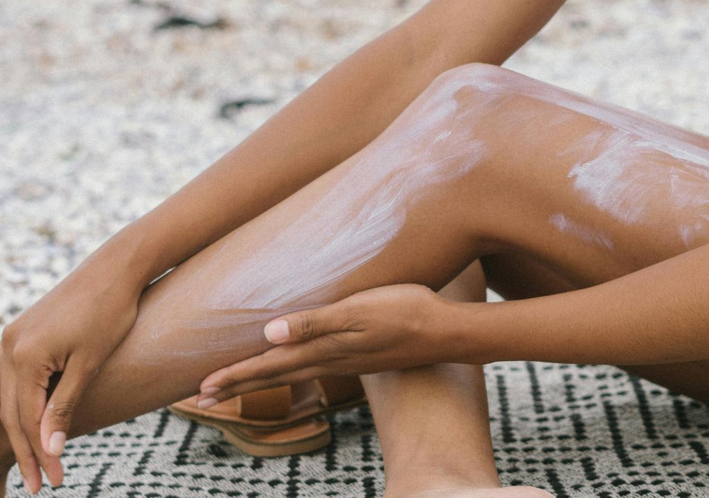 lady applying sunscreen to her legs at the beach