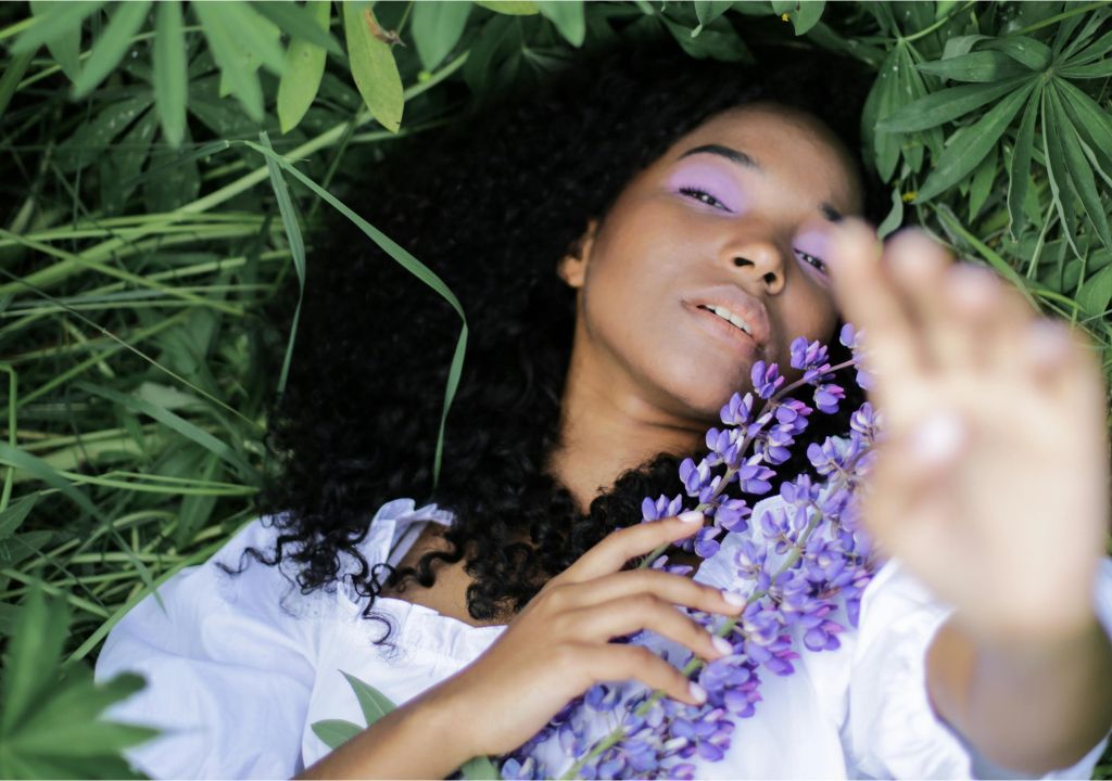 lady laying on the grass surrounded by purple flowers
