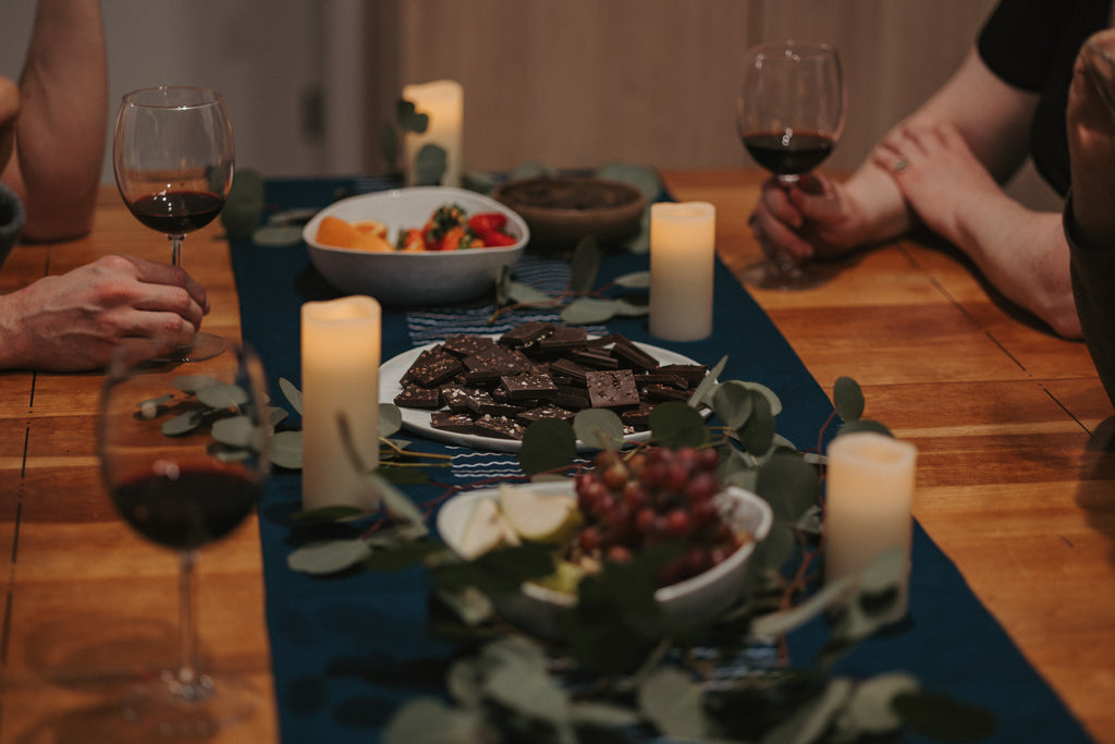 people-sitting-around-table-with-plate-of-chocolates-holding-red-wine-glasses