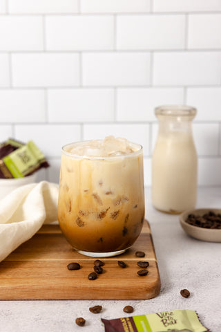 vine-to-bar-latte-and-coffee-beans-on-wood-cutting-board-white-backsplash