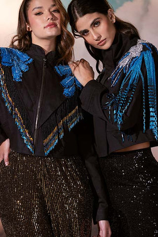 Dos modelos posan con chaquetas negras con bordados de plumas azules en los hombros.
