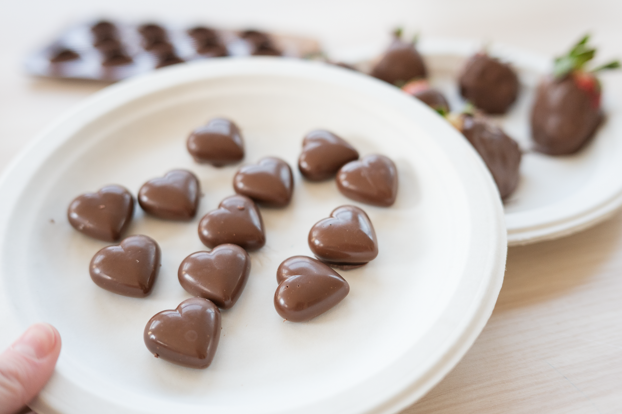 Chocolate hearts with strawberries in the background