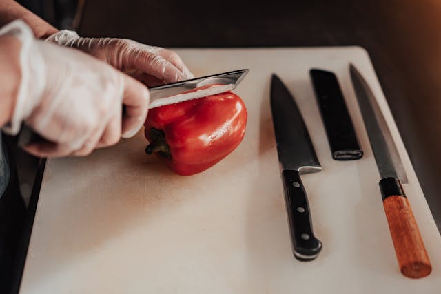 Hand with a knife cuts pepper