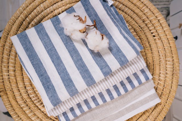 Two cotton flowers lie on a towel in a wicker basket