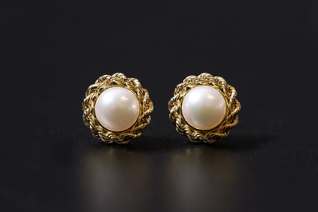 Gold earrings with pearls on a black background