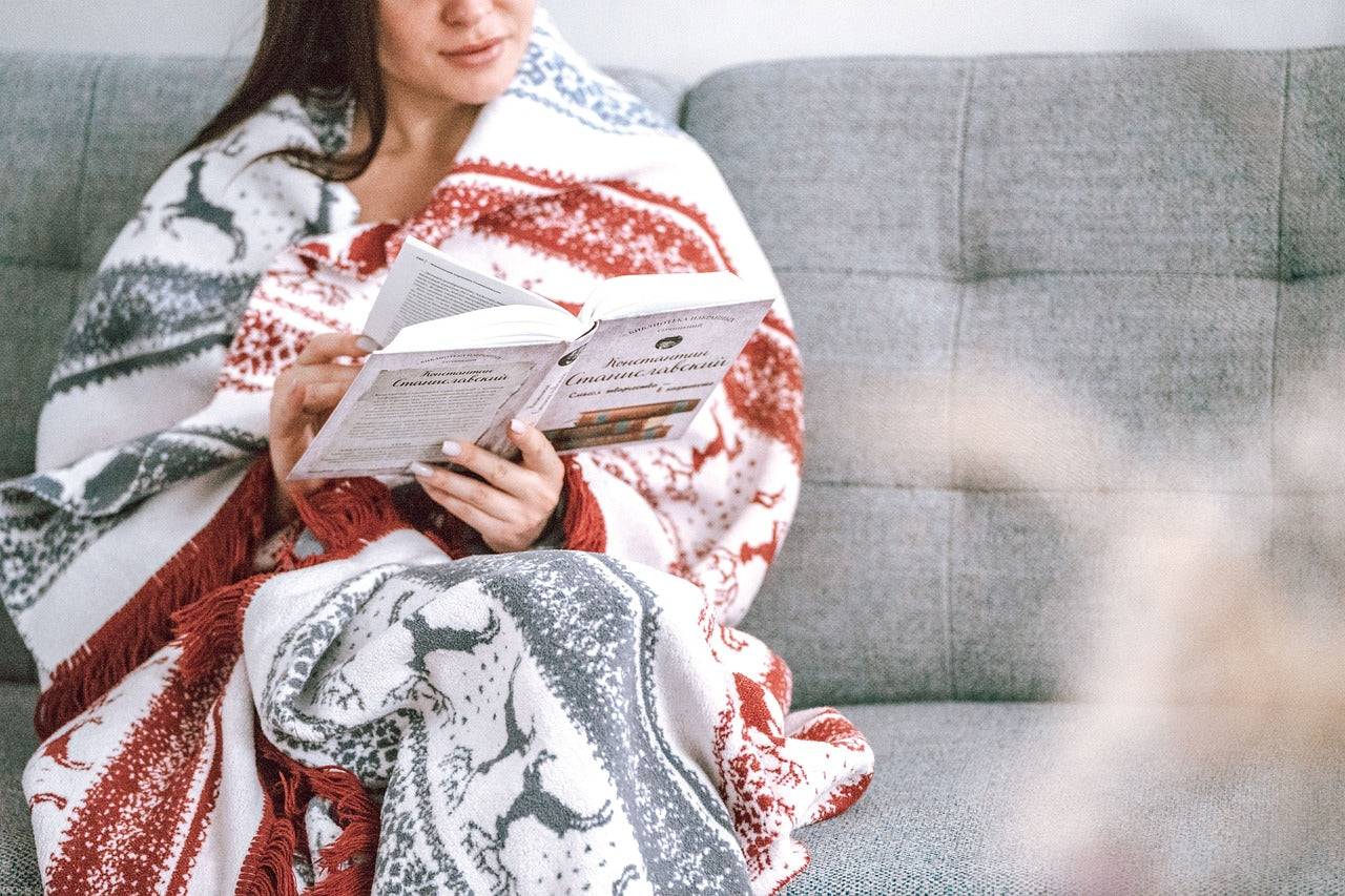 Woman wrapped in a blanket reading a book