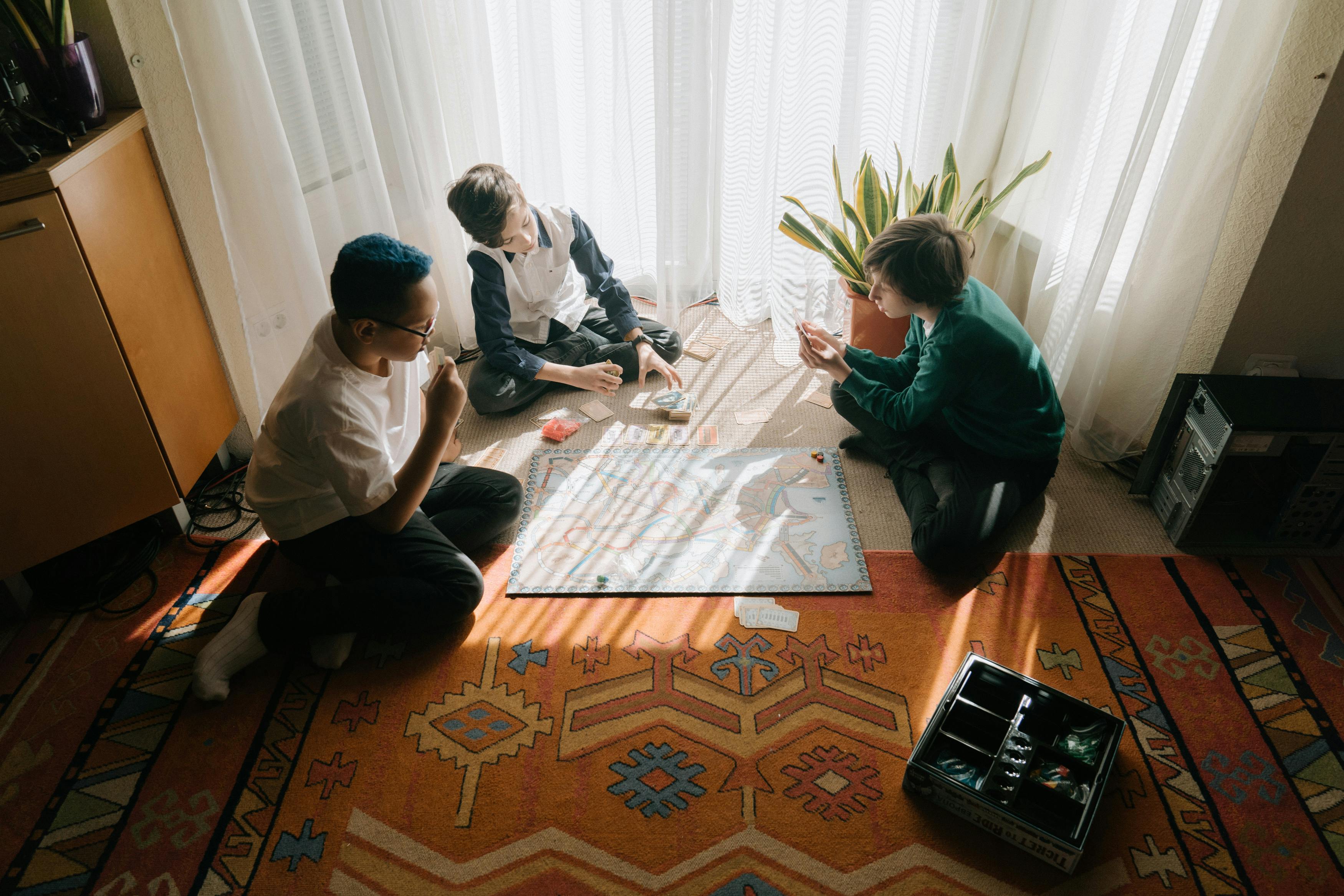 Three people sitting on the floor and playing a board game