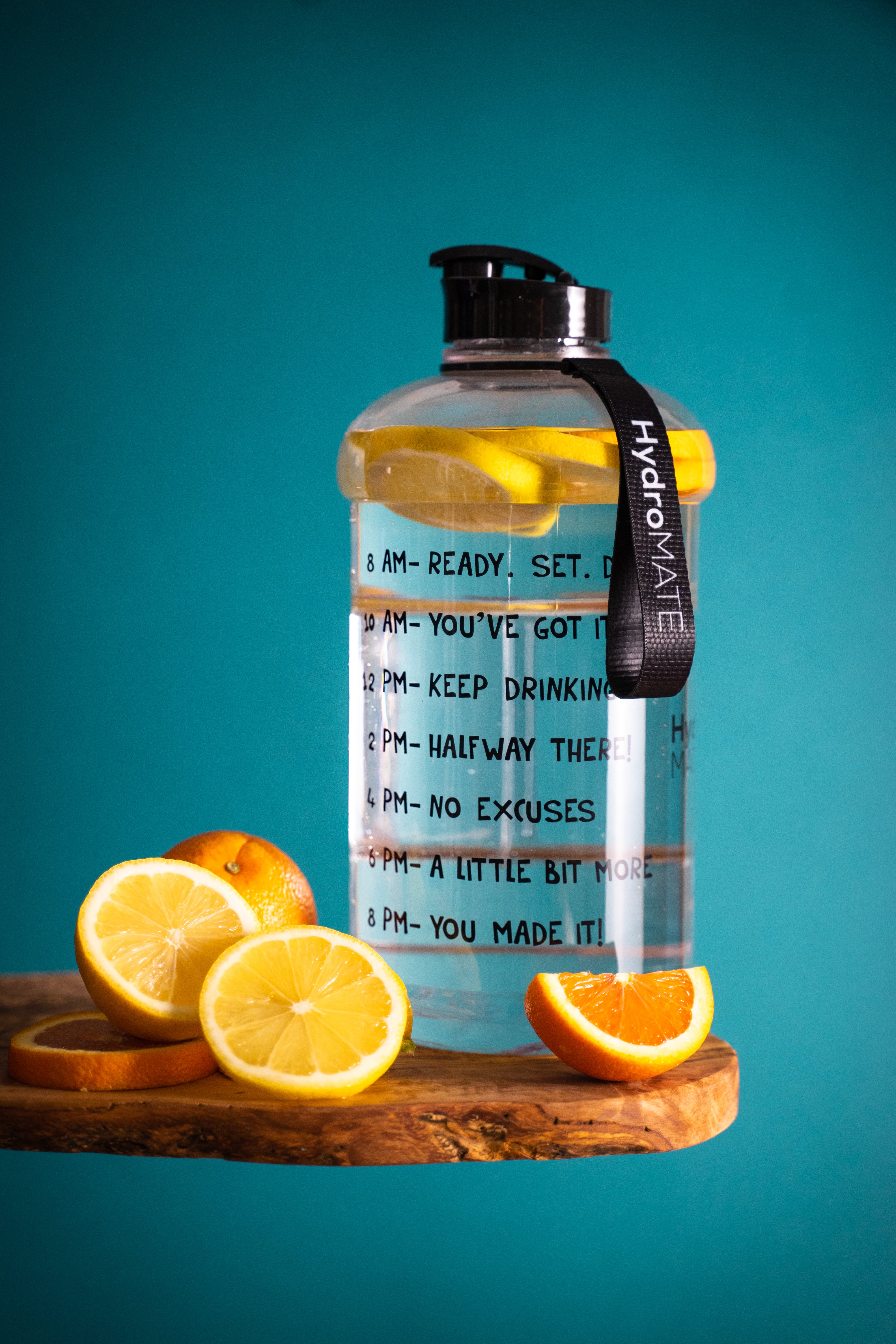 Water bottle with water and orange slices, citrus fruits lying nearby