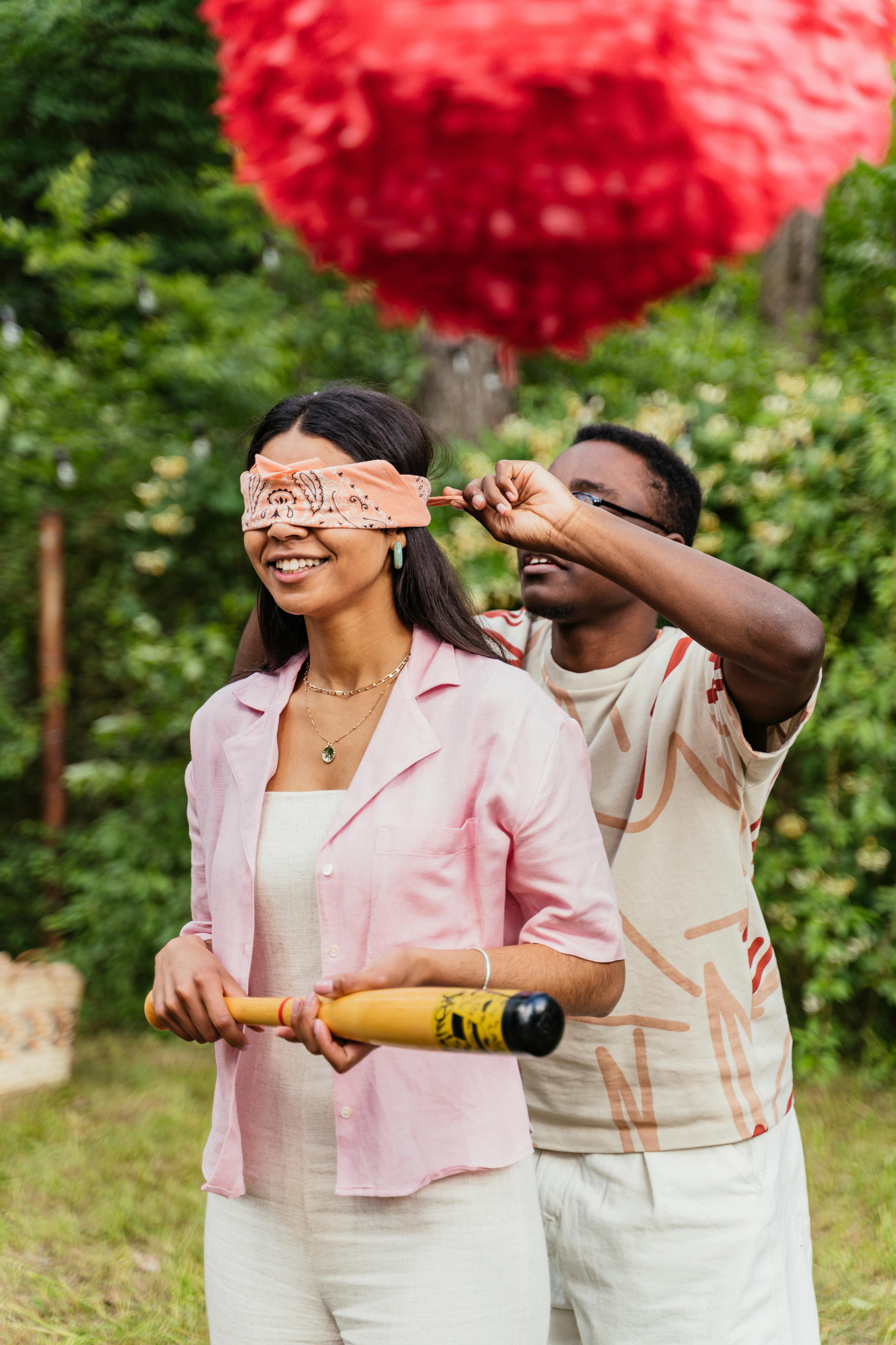 A man blindfolds a girl with a bat