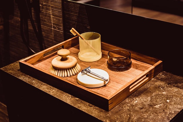 Glass with toothbrush and shaving kit on wooden tray for bathroom