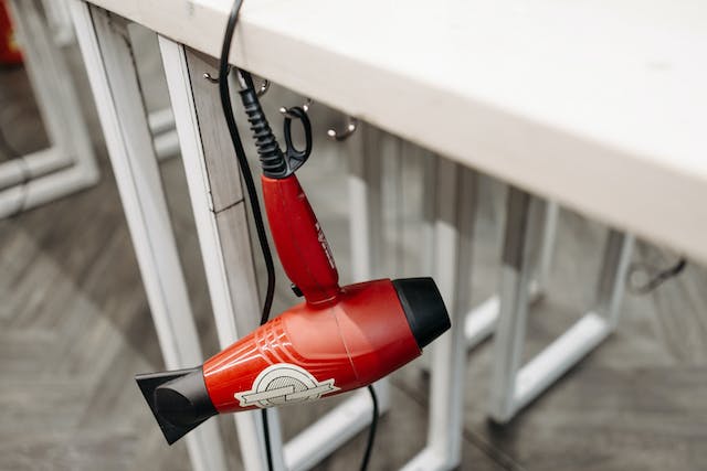 Red hair dryer hanging on a hook