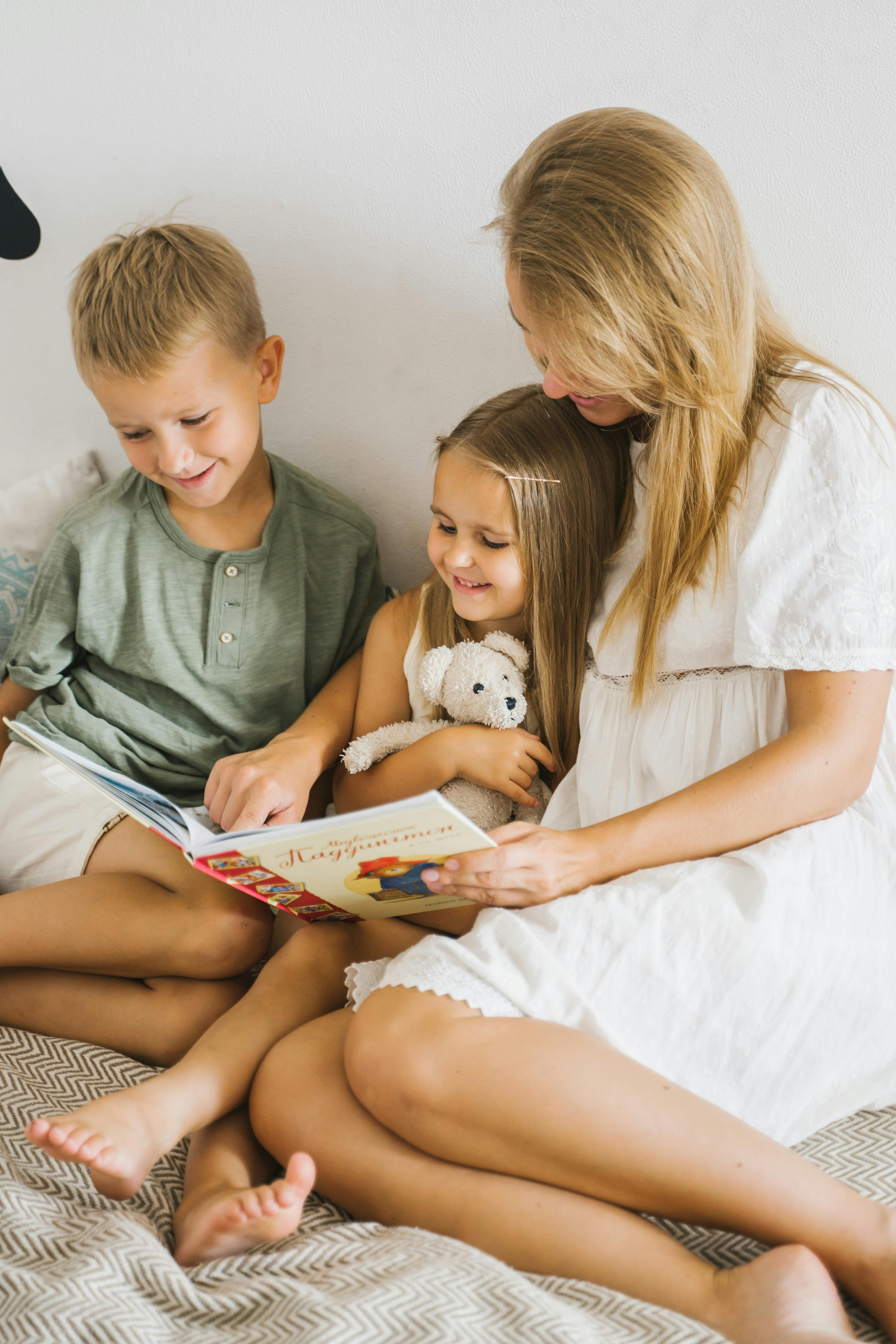 Woman sitting next to two children and reading a book