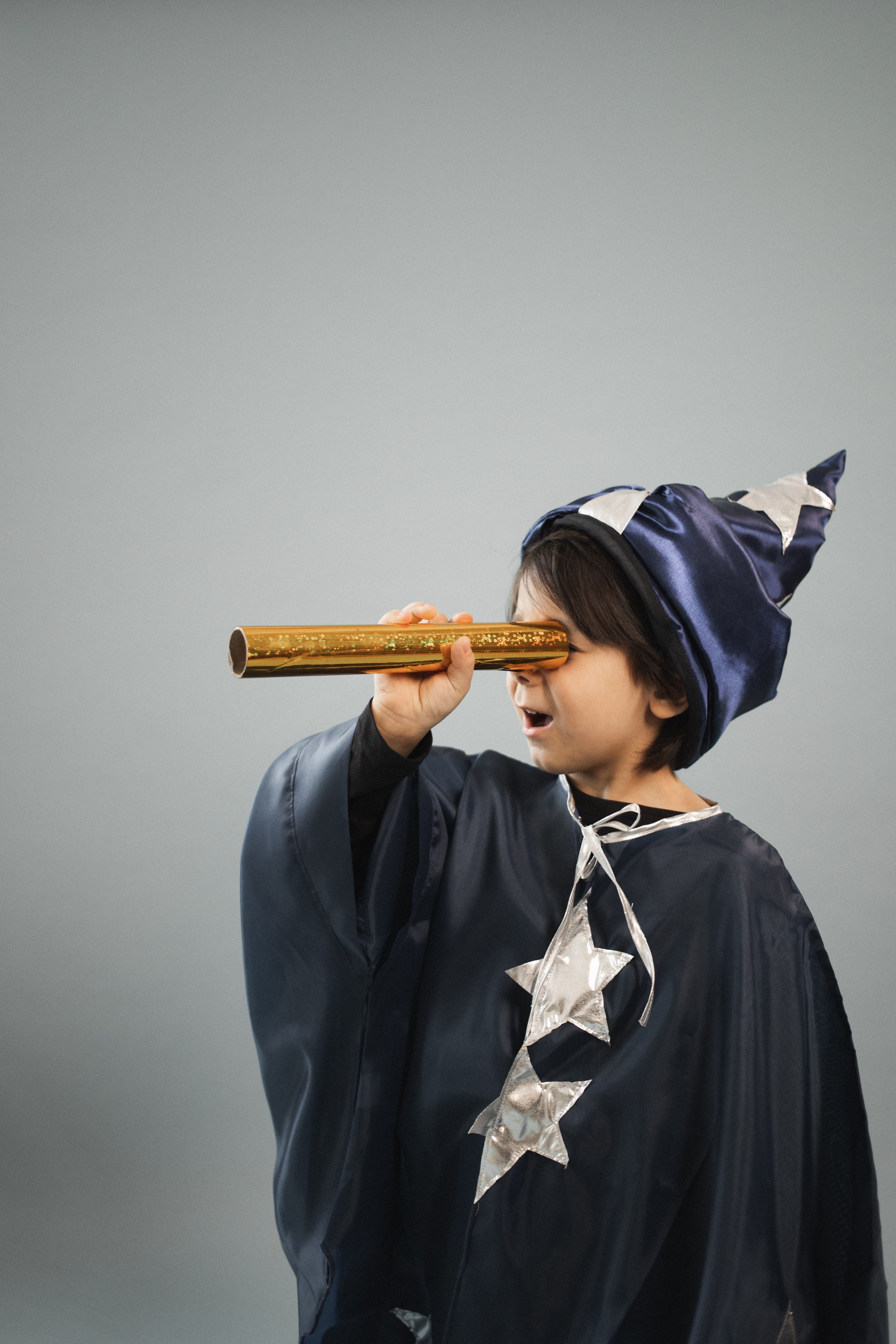 Boy wearing a wizard's robe with star prints and a hat with star prints