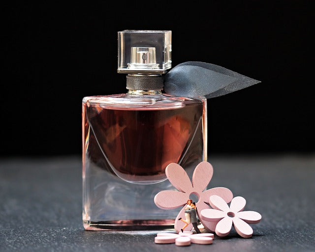 Pink artificial flowers next to a bottle of perfume