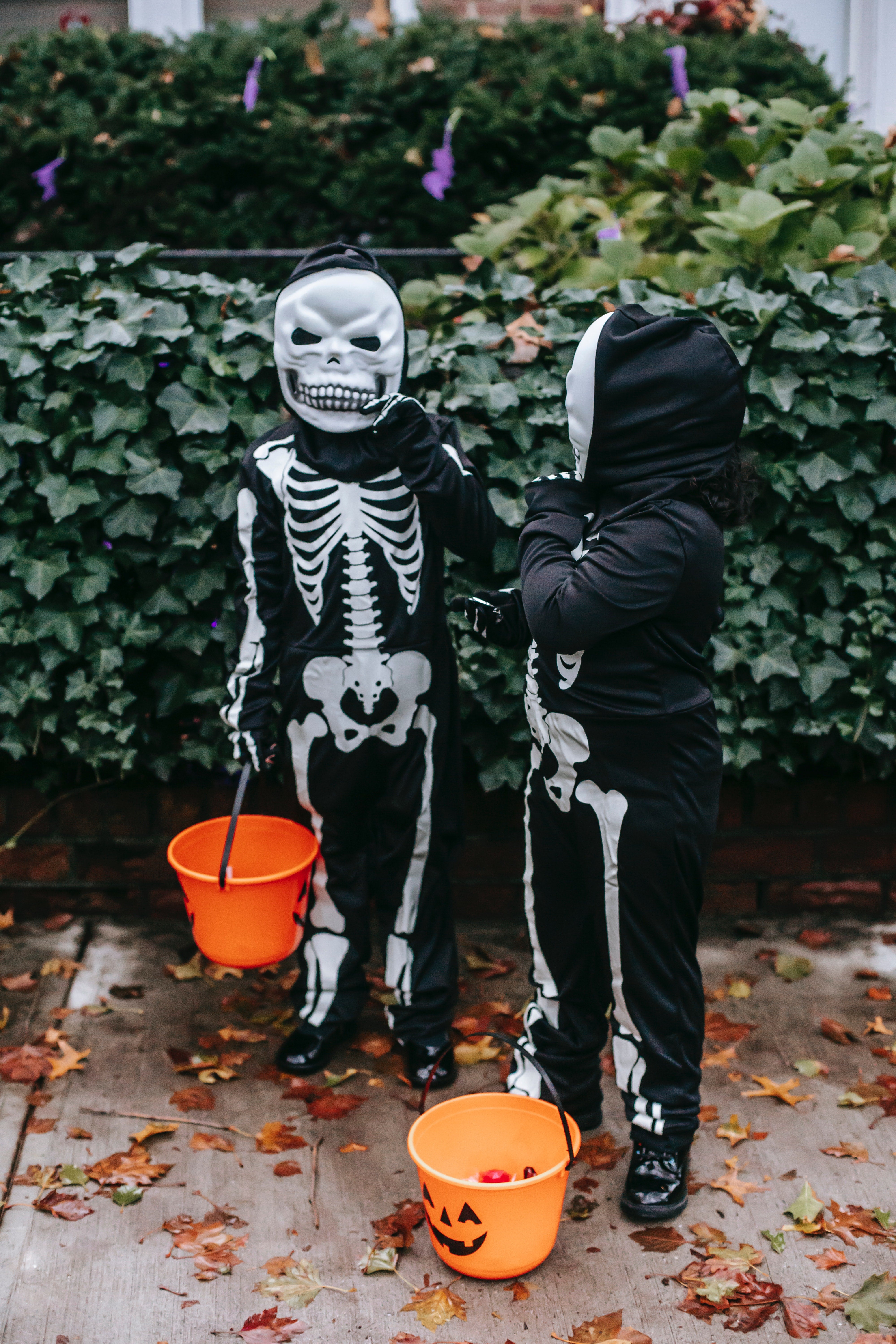 Two boys in skeleton costumes with orange buckets