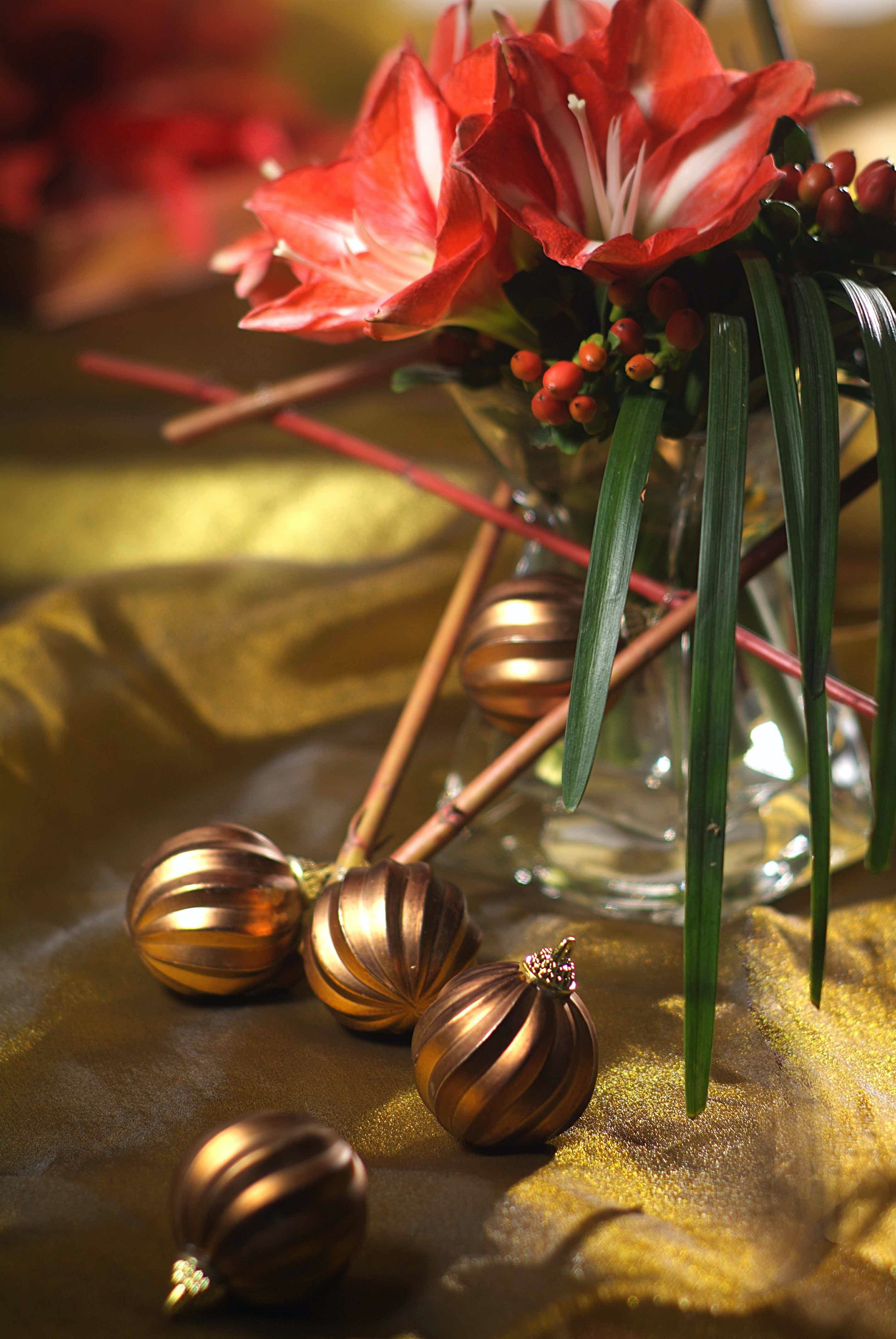 Christmas balls lie in front of a bouquet in a vase