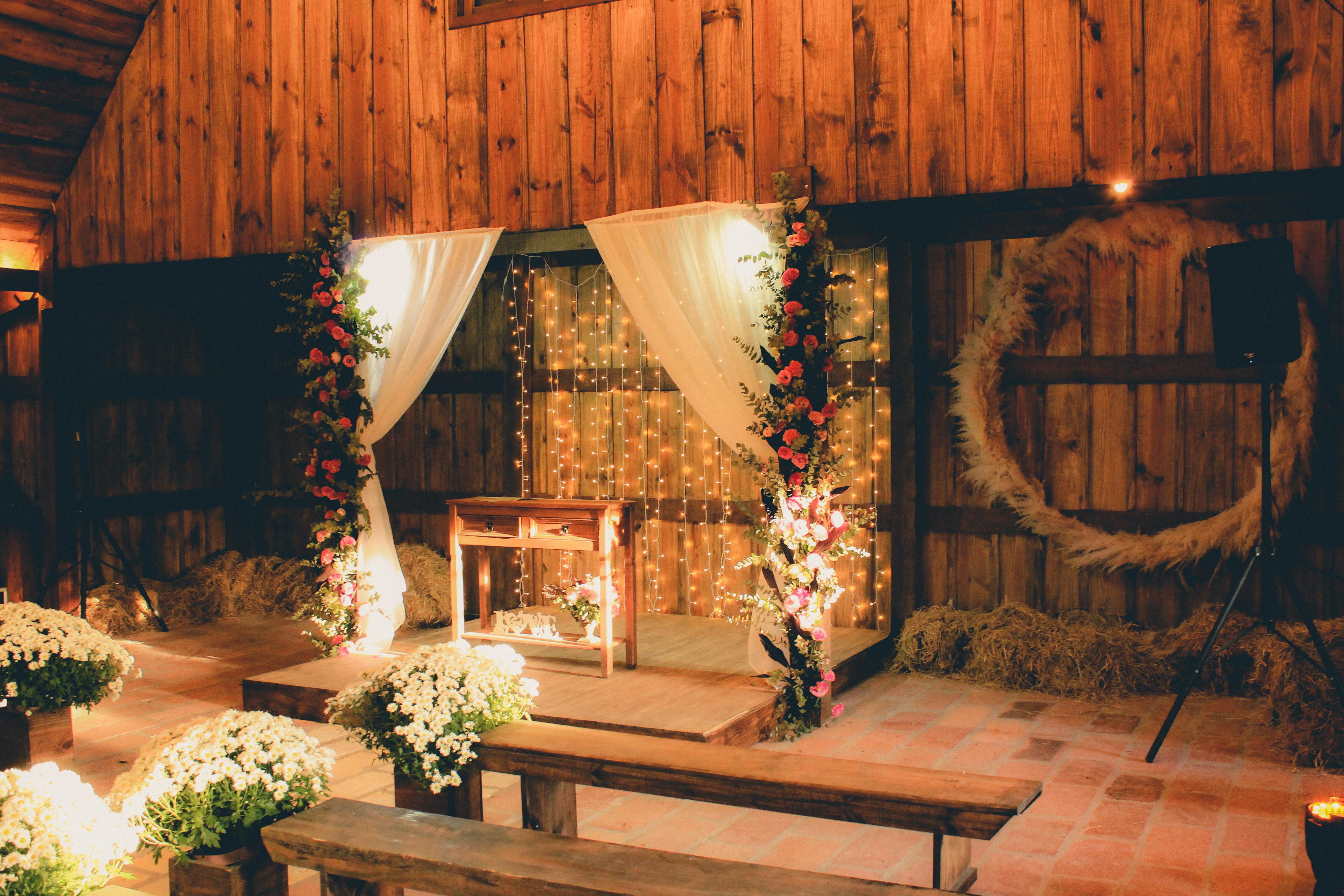 Stage decorated with curtains, glowing garlands and flowers in a wooden building