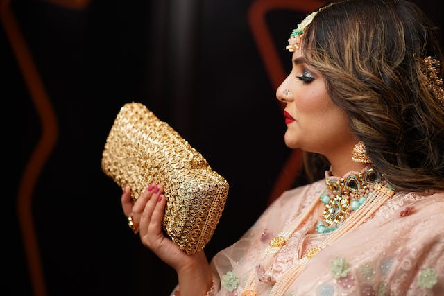 A woman with a lot of jewelry holds a clutch in her hand
