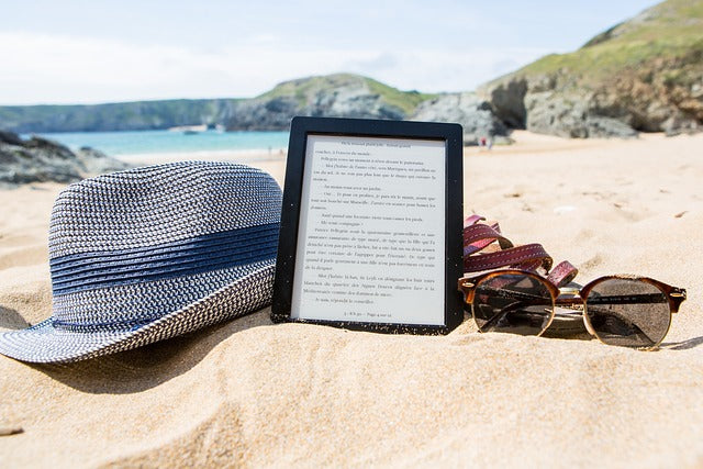 Hat, e-book and sunglasses on the sand