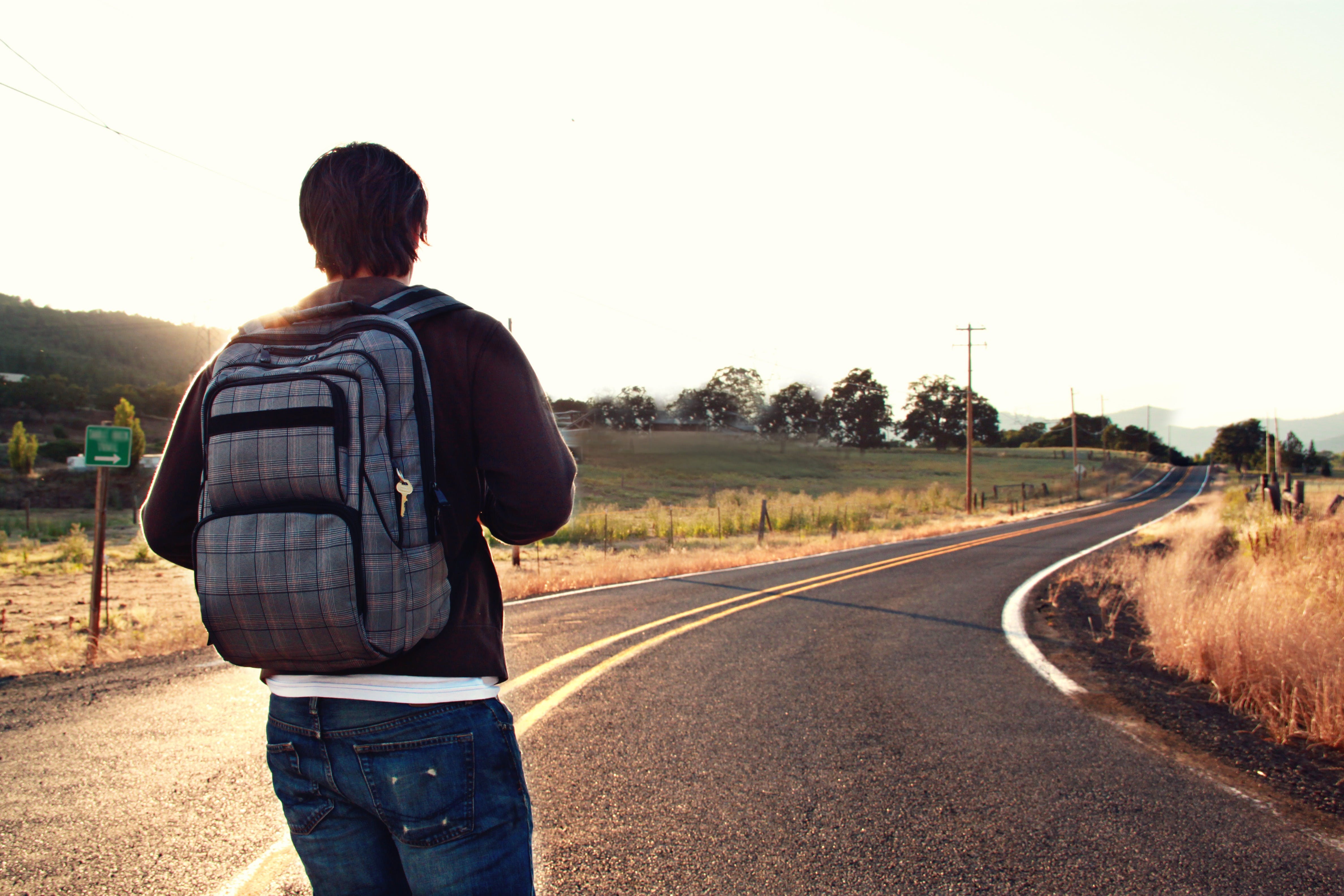 A man with a backpack walks along the road